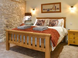 a bedroom with a wooden bed with a stone wall at The Cowshed - Uk50283 in Earl Sterndale