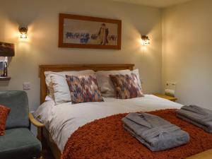 a bedroom with a large bed and a chair at The Cowshed - Uk50283 in Earl Sterndale
