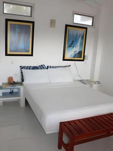 a white bed with two pictures on the wall at Valentina Salchi Bay virgin beaches fast internet in Cuatunalco