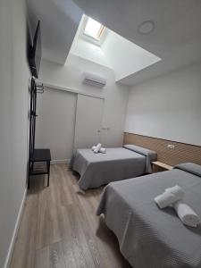 a hotel room with two beds and a skylight at Hostal NV Palacio Congresos in Málaga
