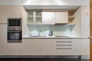 a kitchen with white cabinets and a sink at Tamariz Flat in Santa Cruz