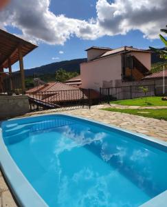 a large blue swimming pool in front of a house at Pedacinho do céu in Tiradentes