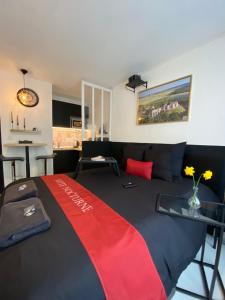 a bedroom with a bed with a red and black blanket at La Suite Nocturne Climatisée avec écran Cinéma in Fère-en-Tardenois