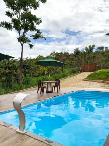 a picnic table with an umbrella next to a swimming pool at Chalé portal da serra in Serra do Cipo