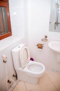 a white bathroom with a toilet and a sink at Kays Place Train house Jambo in Zanzibar City