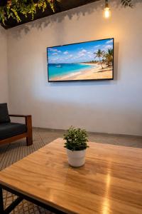 a television hanging on a wall above a wooden table at Djeu Guest House in Santa Maria