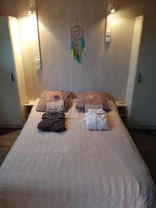 a large white bed with three bags on it at Chalet Zen dans les landes in Castets