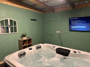 a large bath tub in a room with a tv at Romantic getaway with private hot tub in Belfast +23 photos