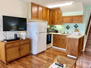 a kitchen with a white refrigerator and wooden cabinets at Unit 11 Beautiful Ocean View in Pahala