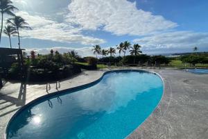 a blue swimming pool with palm trees and a cloudy sky at 58 2 bedroom 2 bath in Pahala