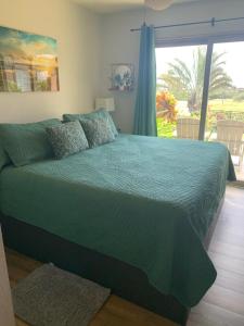 a bedroom with a green bed and a large window at 41 Turtle Hut in Pahala