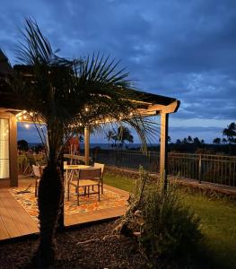 a table and chair on a deck with a palm tree at 37 1 Bed 1 Bath with Ocean Views in Pahala
