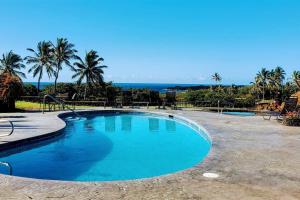 a swimming pool with palm trees and the ocean at 71 Dramatic Ocean and Lava in Pahala