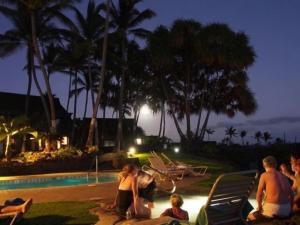 a group of people sitting by a pool at night at 54 Old Hawaii Charm Condo in Pahala +7 photos
