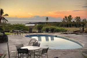 a swimming pool with chairs and a table and a sunset at 70 Pogs Place at Black Sand Beach in Pahala