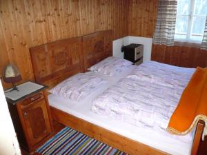 een bed in een kamer met een houten wand bij Almhütte Egger Obheimat in Außervillgraten