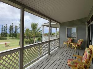 a screened porch with chairs and a table and a view at 2 Bedroom 2 Bath on Golf Course in Naalehu
