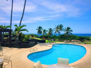 a swimming pool with chairs and the ocean in the background at 16 Two Bedroom Two Bath Condo in Pahala