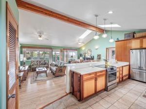 a kitchen with wooden cabinets and a living room at Honu Harbor with Pool on Golf Course in Naalehu