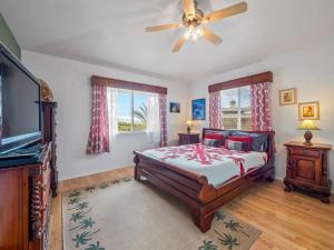a bedroom with a bed and a flat screen tv at Honu Harbor with Pool on Golf Course in Naalehu