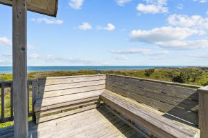 a wooden bench on a deck looking out at the ocean at 2410 - Come Sail Away in Duck