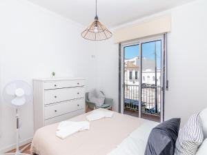 a white bedroom with a bed and a window at Akisol Olhão Sweet in Olhão