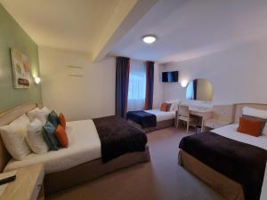 a hotel room with two beds and a dining room at Hôtel Le Kolibri in Tournus