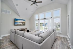 a living room with a large couch and windows at 4918 - Stress Less in Kitty Hawk