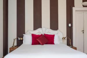 a bedroom with a white bed with red pillows at Opera Boutique B&B in Florence +28 photos