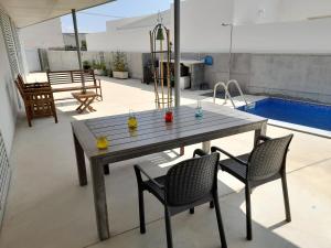 a wooden table and chairs on a patio with a pool at La CASA GRIS in Alcanar