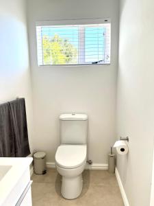 a white bathroom with a toilet and a window at Mountain View Studio Hermanus in Hermanus +6 photos