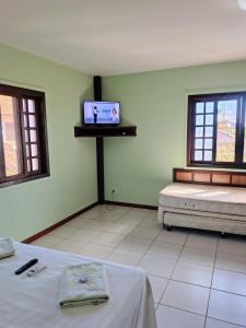 a room with two beds and a tv on the wall at Pousada Paraíso do sul 2 - Carmery in Pontal do Paraná