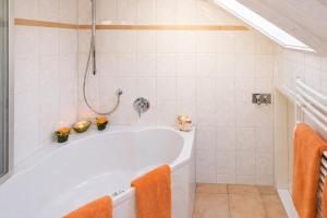 a white bath tub in a bathroom with orange towels at Landhaus Thanner in Ofterschwang