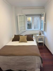 a bed in a bedroom with a table and two windows at A Barca de Pedra in Padrón