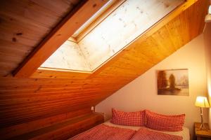 a bed with red pillows in a room with a wooden ceiling at Landhaus Thanner in Ofterschwang +61 photos