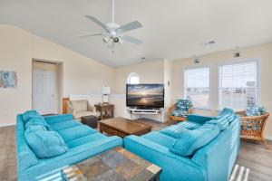 a living room with blue couches and a flat screen tv at 7030 - Waves Against the Machine in Rodanthe
