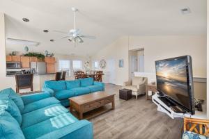 a living room with blue couches and a flat screen tv at 7030 - Waves Against the Machine in Rodanthe +22 photos