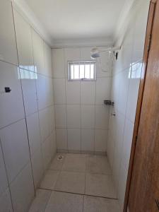a bathroom with white tiled showers and a window at Hostel Araguaia in Goiânia