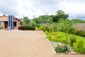 a garden with a brick walkway in front of a house at De Lux Villa in Bulawayo
