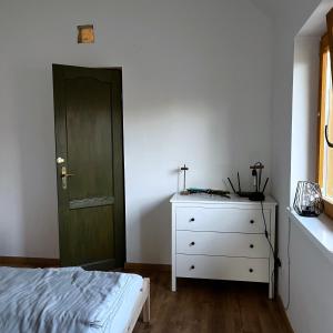 a bedroom with a green door and a white dresser at Kisház in Kisoroszi