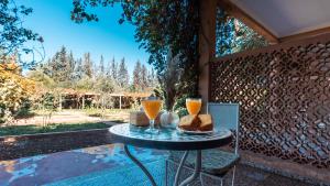 a table with two glasses of orange juice and bread at Le Bled Ferme in Marrakesh