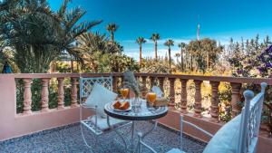a table and chairs on a balcony with palm trees at Le Bled Ferme in Marrakesh