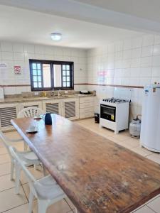 a large kitchen with a wooden table and white appliances at Pousada Paraíso do sul 2 - Carmery in Pontal do Paraná