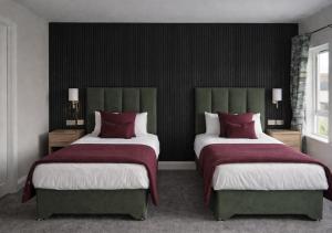 a bedroom with two beds with red and white pillows at Kerry Coast Hotel in Cahersiveen