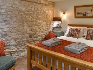 a bedroom with a bed and a stone wall at The Cowshed - Uk50283 in Earl Sterndale