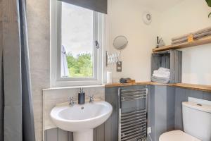 a bathroom with a sink and a window and a toilet at The Burrow in Biddenden +21 photos
