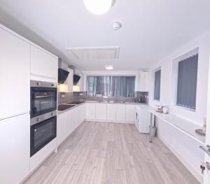 a kitchen with white cabinets and a wooden floor at C- Spacious En-Suite Room Sheffield Centre in Victoria