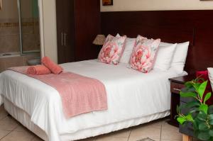a bed with pink and white pillows on it at Ocean View Villas B09 in Port Edward +40 photos