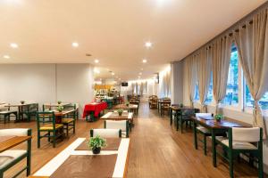 a restaurant with tables and chairs and windows at Hotel Normandie - by Easy Hotéis in São Paulo