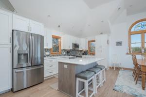a kitchen with white cabinets and a stainless steel refrigerator at 4482 - Villa Al Mare in Duck +25 photos